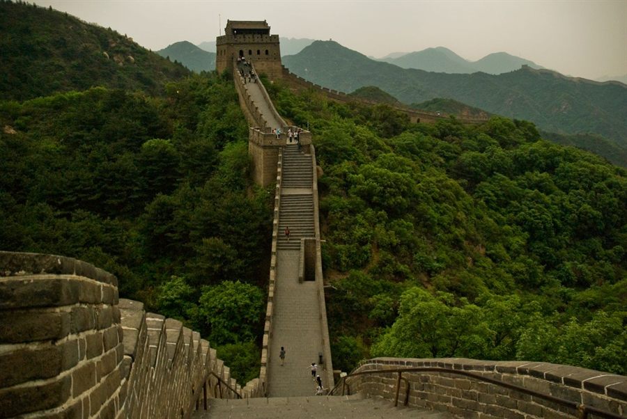 A restored stretch of the Great Wall climbing a green ridge toward a watchtower
