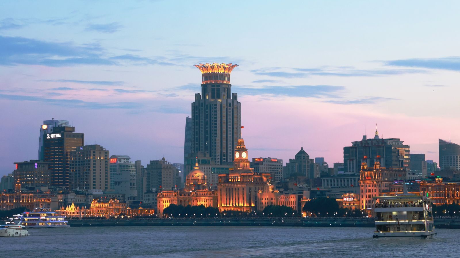 The historic buildings of the Bund in Shanghai at dusk with riverboats on the Huangpu, where a Yangtze river cruise from Shanghai begins